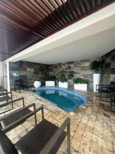 una piscina en una habitación con bancos y sillas en Hotel poseidon piscina & jacuzzi, en Manta