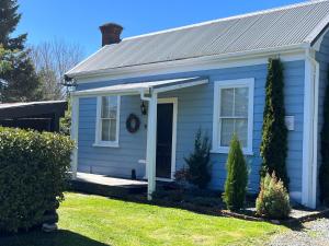 ein blaues Haus mit einer Veranda und einer Tür in der Unterkunft Kosbys Cottage, Tongariro 