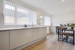 a large kitchen with white cabinets and a table at 17 Banstead Road in Poole