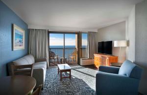 um quarto de hotel com um sofá e uma televisão e uma sala de estar em Dayton House Resort - BW Signature Collection em Myrtle Beach