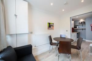 a living room with a table and chairs and a kitchen at Cozy 2-Bedroom Flat in Battersea in London