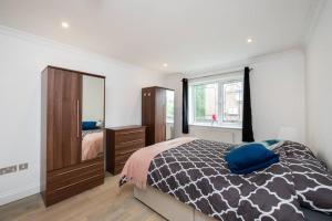 a bedroom with a bed and a dresser and a mirror at Cozy 2-Bedroom Flat in Battersea in London