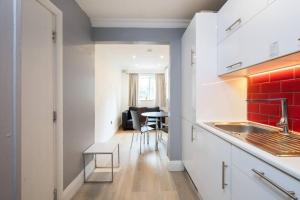 a kitchen with white cabinets and a red brick wall at Cozy 2-Bedroom Flat in Battersea in London