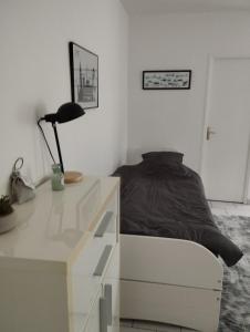 een slaapkamer met een bed en een bureau met een lamp bij studio charmant canapé lit Netflix Prime video in Le Havre