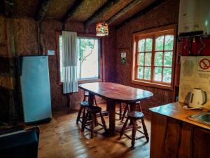 a kitchen with a table and a refrigerator and a window at Hostal & Cabañas Luna del Sur in Cucao