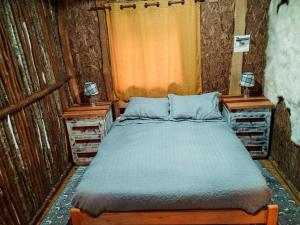 1 dormitorio con 1 cama y 2 mesitas de noche en Hostal & Cabañas Luna del Sur, en Cucao