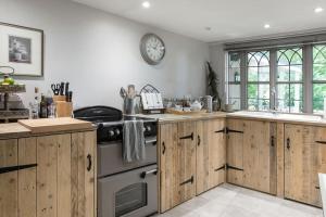 a kitchen with wooden cabinets and a clock on the wall at Magical and Romantic Countryside Getaway Near Windsor Castle in Old Windsor