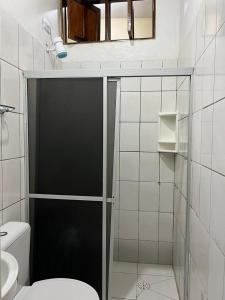 a bathroom with a toilet and a glass shower door at Casa Oceano in Marechal Deodoro