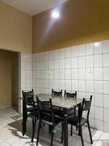 une table avec des chaises noires et une table, ainsi qu'une chambre avec du carrelage blanc dans l'établissement Casa Oceano, à Marechal Deodoro