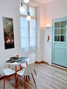 uma sala de jantar com uma mesa e cadeiras brancas em Appartement cosy centre-ville. em Perpignan