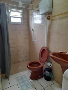uma casa de banho com um WC castanho e um lavatório. em Linda kitnet perto do mar! em Tramandaí