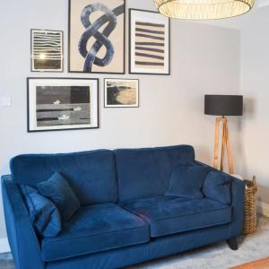 eine blaue Couch in einem Wohnzimmer mit Bildern an der Wand in der Unterkunft Avocet Cottage Amble in Amble