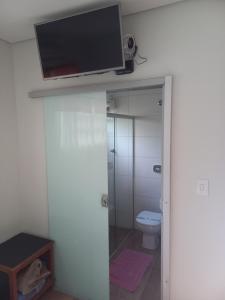 ein Bad mit einem WC und einen TV an der Wand in der Unterkunft Pousada Rural Veredas in Três Marias