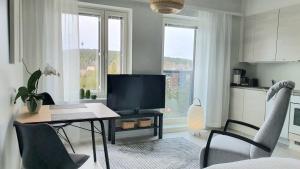 - un salon avec un bureau, une télévision et des chaises dans l'établissement Studio 12 floor, Puijo landscape, Free parking, à Kuopio