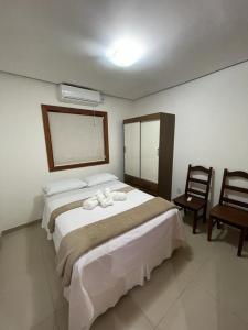a bedroom with a large bed and two chairs at Escalada Hospedagem Térreo in Mucugê