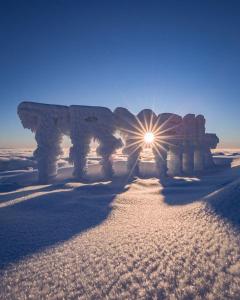 a sun shining on a stone structure in the snow at Solbjørnlia Apartments in Trysil