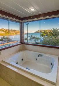 uma grande banheira num quarto com janelas em Cinematográfica Mansão Pé na Areia da Ferradura com Treze Quartos Por Luxury Rentals em Búzios
