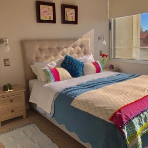 1 dormitorio con 1 cama grande y almohadas coloridas en Departamento Costa Reñaca, en Viña del Mar
