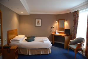 Habitación de hotel con 2 camas, escritorio y espejo. en Preston Park Hotel, en Brighton & Hove