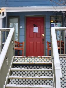 a red door on a blue house with stairs at Hidden Valley Bed and Breakfast in Whitehorse