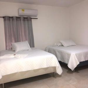 a room with two beds and a air conditioner at Hotel Samark Valledupar in Valledupar