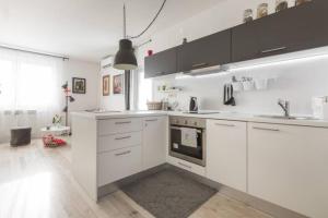 a kitchen with white cabinets and a large window at New Studio Apartment Sun in Zagreb