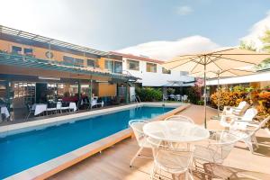 a pool with tables and chairs and an umbrella at Hotel Puerta del Sol - San Jose Airport in San José