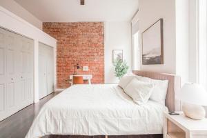 1 dormitorio con cama blanca y pared de ladrillo en Light and Airy, Spacious 2B 2Bath Downtown City View, en Cincinnati