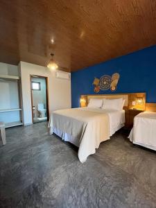 um quarto com 2 camas e uma parede azul em Pousada Lençóis Eco Villa em Santo Amaro