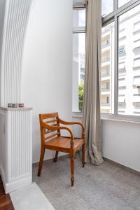 a wooden chair sitting in front of a window at Apartamento aconchegante em Copacabana - Rio de Janeiro in Rio de Janeiro