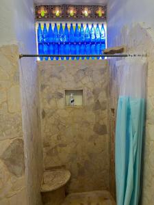 baño con ducha con botellas azules en la pared en AFRO HOSTEL, en Necoclí