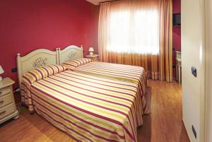 una camera da letto con un letto con una coperta a righe e una finestra di LOCANDA LE 4 CIACOLE a Roverchiara