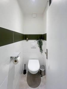 a white bathroom with a toilet and a plant at Auteuil • 4 Chambres • Wifi • Métro à 400m in Rennes