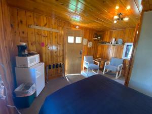 Habitación con paredes de madera y cocina con nevera. en Cabin 8 at Horse Creek Resort en Rapid City