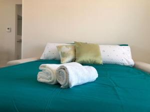 Una cama verde con toallas y almohadas. en Casa dei sogni 20 minuti dal Duomo MM1, en Sesto San Giovanni