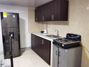 La cuisine est équipée d'une cuisinière, d'un évier et d'un réfrigérateur. dans l'établissement Apartamentos Quimbaya, à Quimbaya