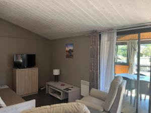 salon z kanapą, łóżkiem i telewizorem w obiekcie Le Chalet de la Folie w mieście Corcieux