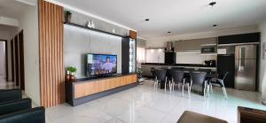 a kitchen and living room with a tv and some chairs at Linda casa no baln. Ponta do papagaio a 100m do mar in Palhoça