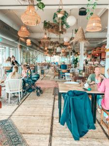 um grupo de pessoas sentadas em mesas em um restaurante em Het VaarHuis - Beachclub Sneek em Offingawier