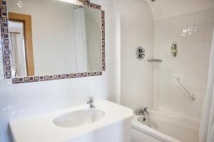 a bathroom with a sink and a tub and a mirror at The Waters Edge in Rathmullan