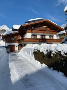 a house is covered in snow with a driveway at Haus Sommerstein in Maria Alm am Steinernen Meer