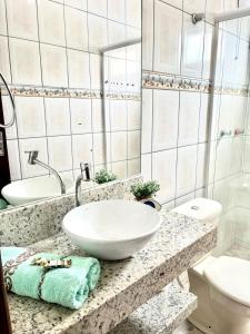 ein Badezimmer mit einem weißen Waschbecken und einem WC in der Unterkunft Férias de Verão - Bombinhas in Bombinhas