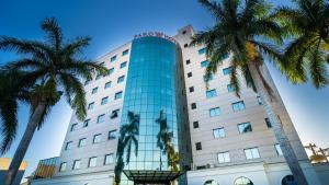 a hotel with palm trees in front of it at Faro Hotel Taubaté in Taubaté