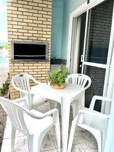 einen weißen Tisch und 4 Stühle auf einer Terrasse in der Unterkunft Férias de Verão - Bombinhas in Bombinhas