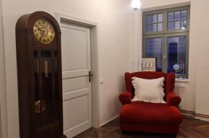 un reloj y una silla roja en una habitación en Historisches Badehaus, en Hoym
