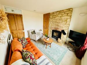 sala de estar con sofá naranja y chimenea de piedra en Cotswold Home over 4 floors - perfect for Families Friends Contractors, en Chipping Norton