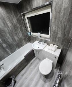 a bathroom with a toilet and a sink and a tub at Stunning 3 bedroom FMHomes & Apartments in Uddingston