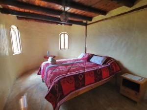 a bedroom with a bed with a red blanket and two windows at Refugio Samay Toa in Hacienda Gualovi