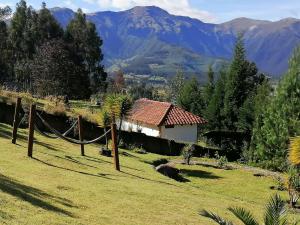 a house in a field with mountains in the background at Refugio Samay Toa in Hacienda Gualovi