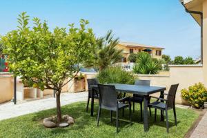 una mesa y sillas y un árbol en un patio en [2 KM DAL MARE] Villetta relax con barbecue, en Palmadula